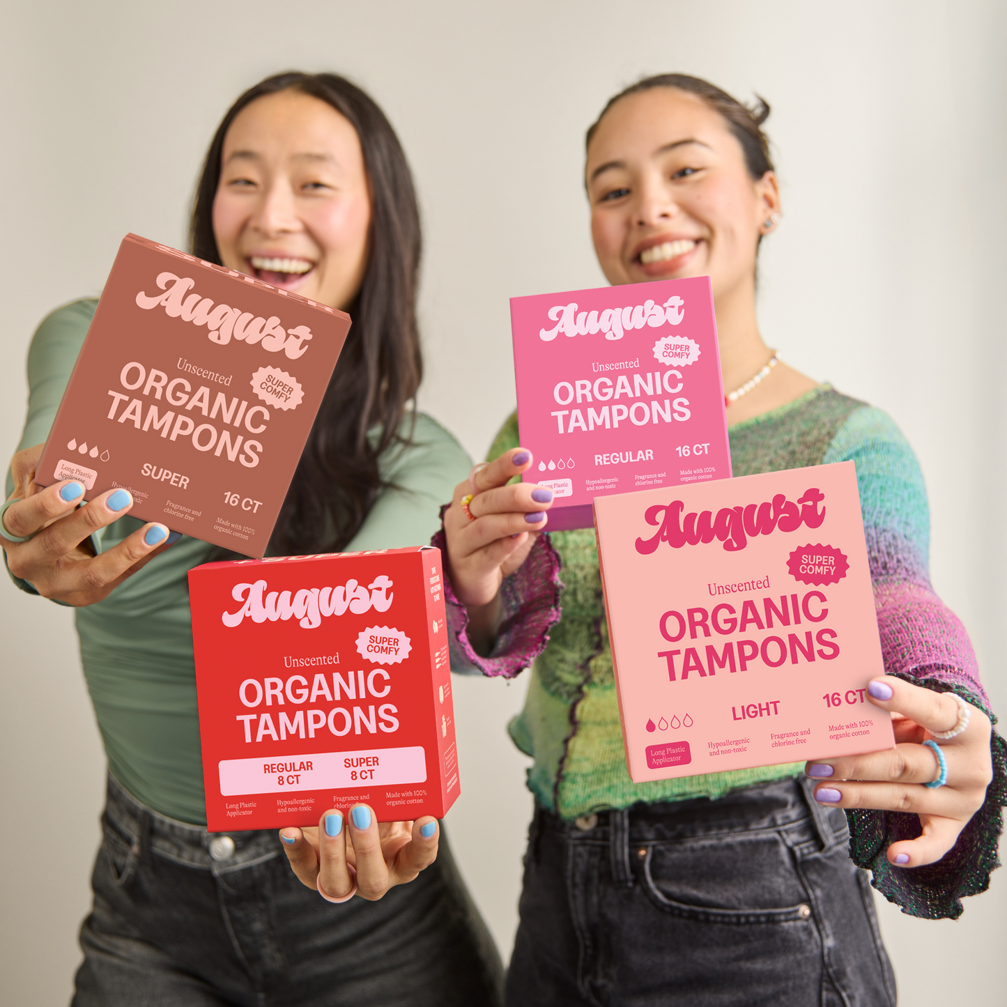 Two people holding packages of August organic tampons against a plain background